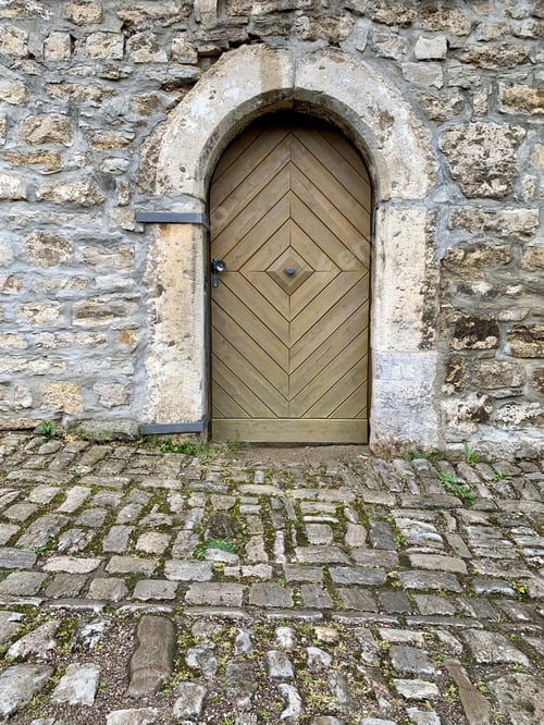 Preview: Vertical shot of an old stone-made building facade wit arched doorway and wooden door