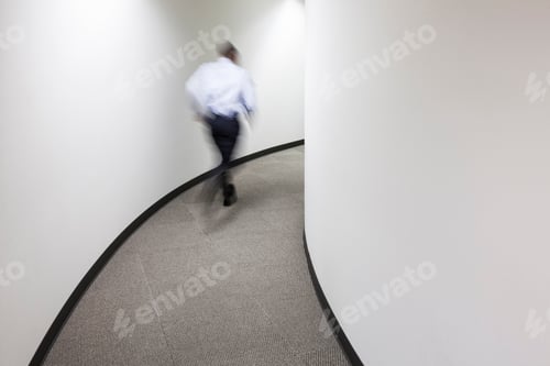 Preview: A blur of a businessman running in an office hallway.