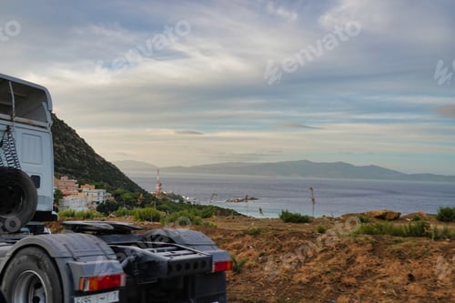Preview: Truck parked on a rural road near the sea under a cloudy sky
