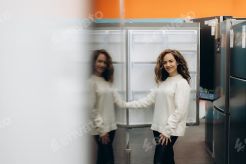 Preview: Young Woman Smiling While Shopping for Refrigerators in an Electronics Store