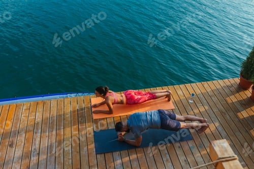 Preview: Couple doing a yoga near lake early in the morning