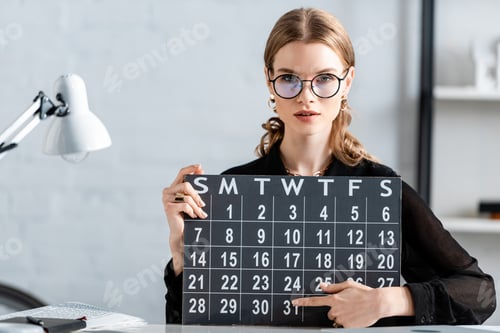 Preview: businesswoman in black clothes and glasses holding calendar and sitting on chair