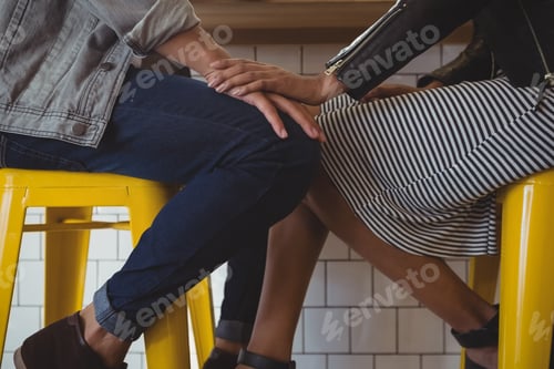 Preview: Low section of young couple on stool in cafe
