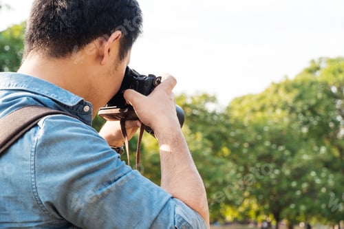 Preview: Back view of Asian male photographer taking picture with camera