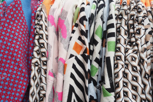 Preview: Colorful knitted sweaters displayed at a vibrant market stall