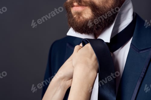 Preview: man in suit tying tie elegant style dark background