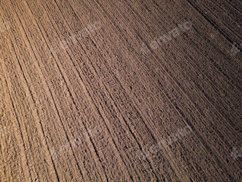 Preview: Freshly plowed soil with evenly spaced furrows, creating a textured pattern across the surface. The