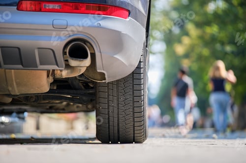 Preview: Close up of car rear wheel and exhaust pipe parked on city street side