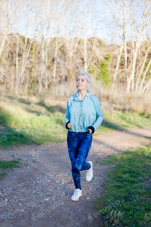 Preview: Fit healthy young woman enjoying a jog along a country road