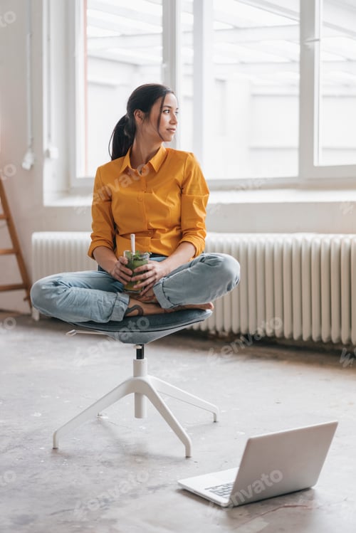 Preview: Yung woman sitting in her new flat with a laptop