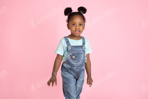 Preview: Cute little African preschool girl, wearing casual jeans overalls and t-shirt, posing to camera on