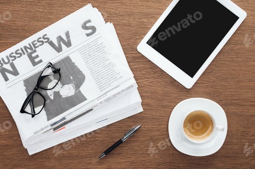Preview: elevated view of cup of coffee, pen, tablet with blank screen and business newspapers on wooden