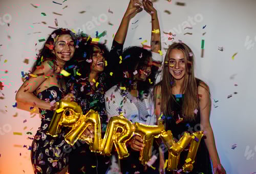 Visualização: Grupo de jovens comemorando com confetes, em pé dentro de casa