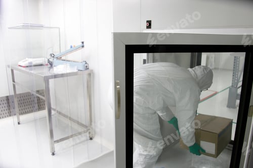 Preview: Worker in Clean Suit Lifting Cardboard Box