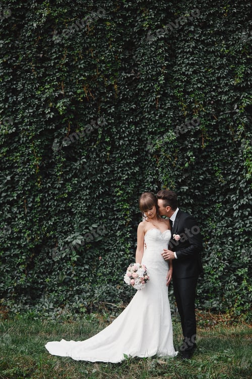 Preview: bride in a long white dress with a wedding bouquet along with a groom in a stylish suit after a wedd