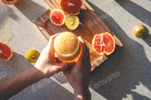 Preview: Woman hand with juice glass and oranges on kitchen table background., top view.