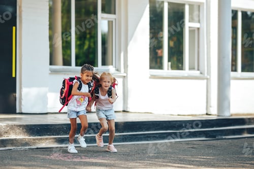 Preview: Two schoolgirls holding each other's hands flee from school, back to school, primary education