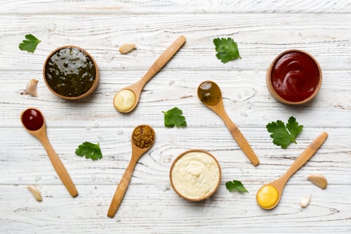 Preview: Different sauces in spoons on table background, flat lay top view
