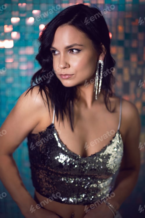 Preview: portrait sexy young energetic woman in silver clothes in the studio against a background of shiny