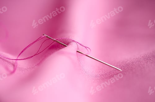Preview: sewing needle with thread stuck into pink fabric