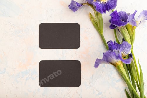Preview: Black business card with blue iris flowers on white concrete background. top view, copy space.