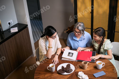 Preview: Three Generation Family Women Reviewing Photo Album at Home