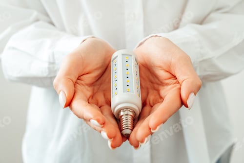 Preview: Woman in white shirt holding light bulb in hand