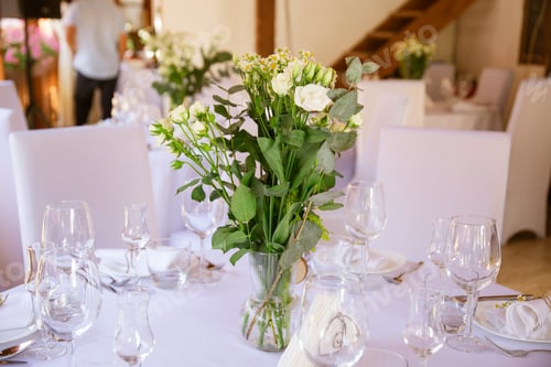 Preview: Wedding reception table with dishes and drinks decorated with a vase of flowers.