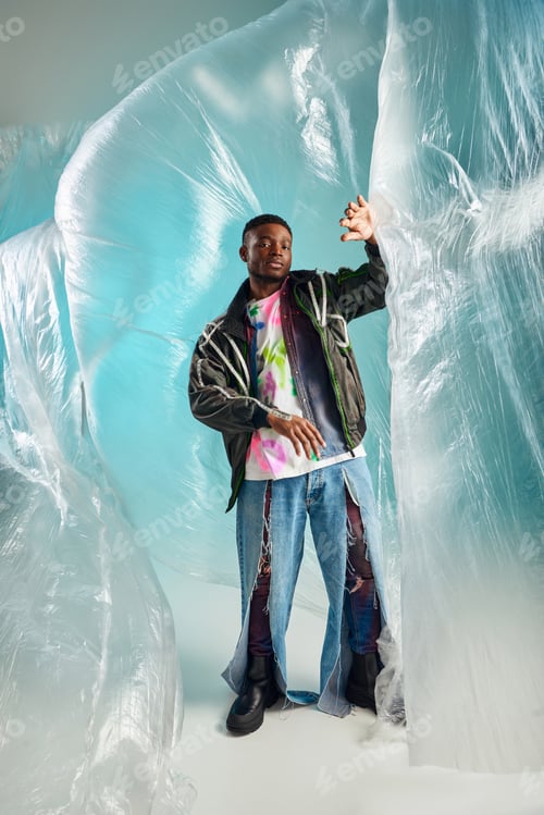 Preview: Full length of trendy young african american man in ripped jeans and outwear jacket