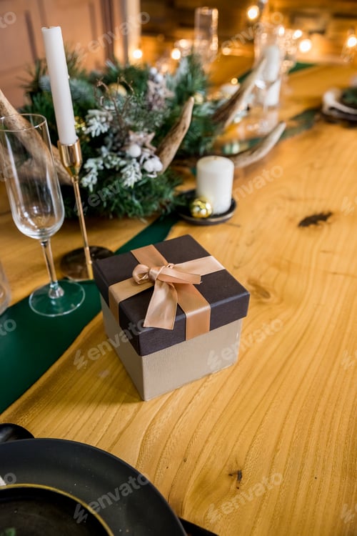 Preview: Christmas dinner in living room.On a wooden table are festive plates, wrapped boxes of gifts, candle