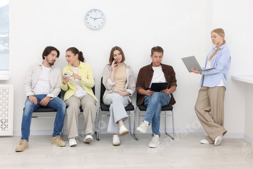 Preview: People waiting in queue on chairs indoors