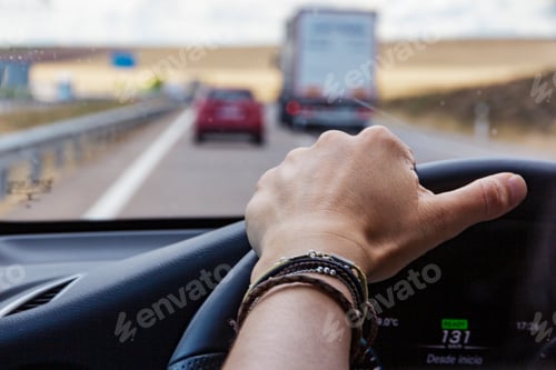 Preview: Female hand on the steering wheel driving a car in a highway, road trip on vacation