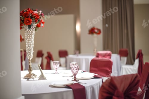 Preview: Festive table setting in banquet hall with red bouquets