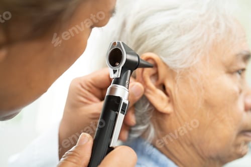 Preview: Audiologist or ENT doctor use otoscope checking ear of asian senior woman