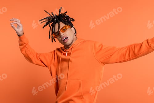 Preview: multiracial man in stylish sunglasses posing with opened mouth isolated on coral background