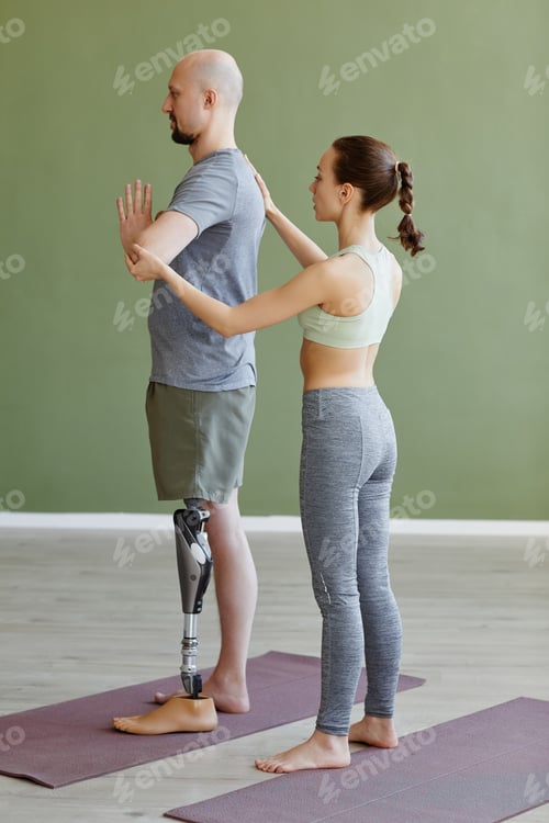 Preview: Man with prosthetic leg doing yoga indoors female instructor