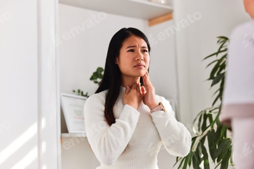Preview: A painful Asian patient having tonsils problems, sitting with a female doctor.