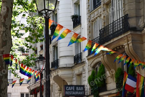 Preview: Bright garlands of striped triangle banners in colors of LGBTQ flag on street of Paris France