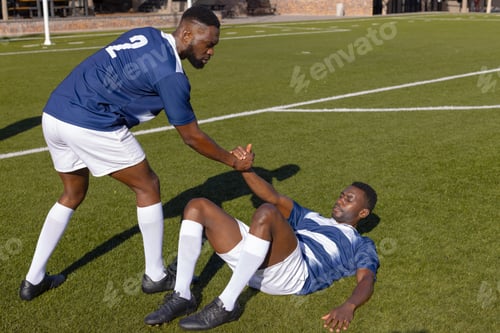 Preview: Two African American male athletes play rugby, one helping the other up