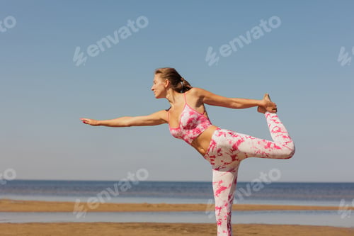 Preview: happy woman does yoga and fitness on sandy beach by sea. warm up stretching