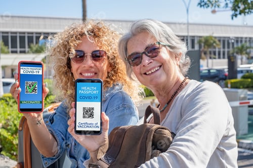 Preview: Two smiling women ready to travel show digital health certification for people vaccinated of covid
