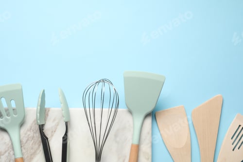 Preview: Different spatulas, whisk and tongs on light blue background, flat lay. Space for text