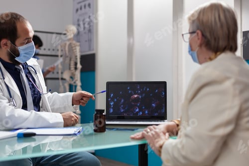Preview: Specialist and patient looking at virus presentation on laptop