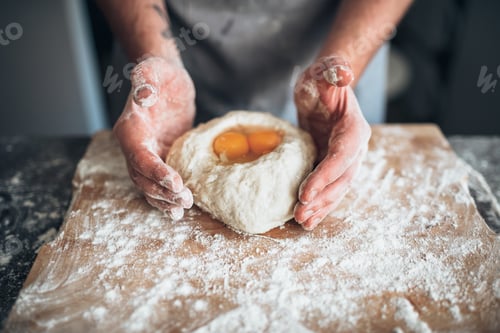 Preview: Male baker hands mix the dough with egg