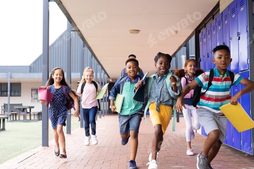 Preview: Diverse male teacher with happy children running in elementary school corridor, copy space