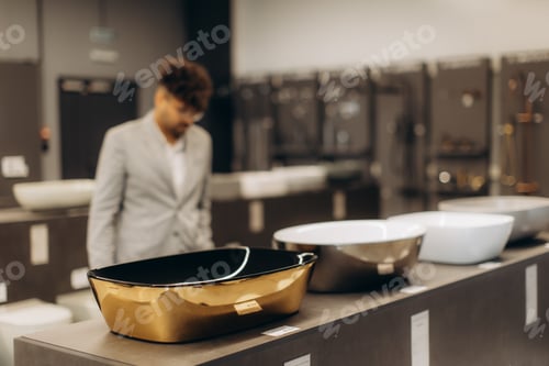 Preview: Man Examining Modern Designer Washbasins in a Stylish Showroom