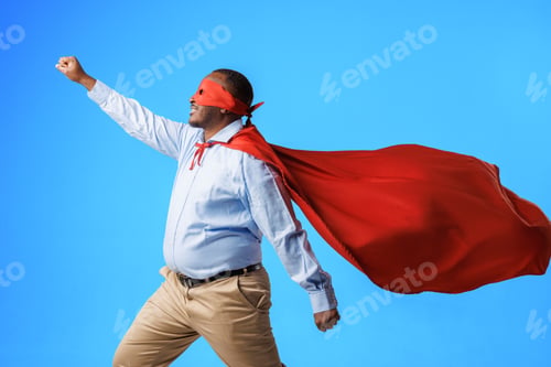 Preview: African American overweight guy in superman costume, in flying pose on blue background