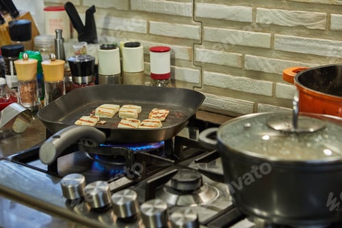 Preview: Halloumi cheese is fried on ribbed pan over fire on gas stove