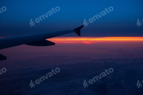 Preview: Sunset view from an airplane. Flying over the clouds in colorful sunset