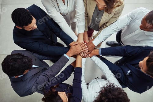 Preview: High angle shot of a group of businesspeople joining their hands together in unity